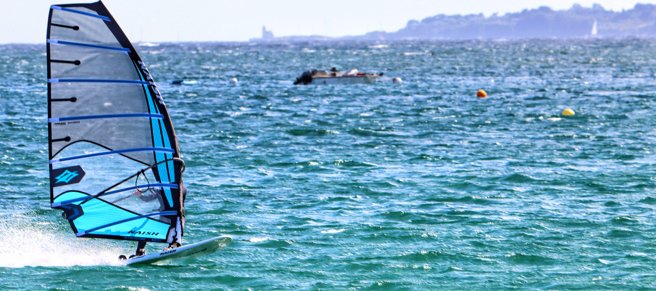 Windsurfer sailing at high speed, illustrating how forward motion creates induced wind and changes the apparent wind angle.