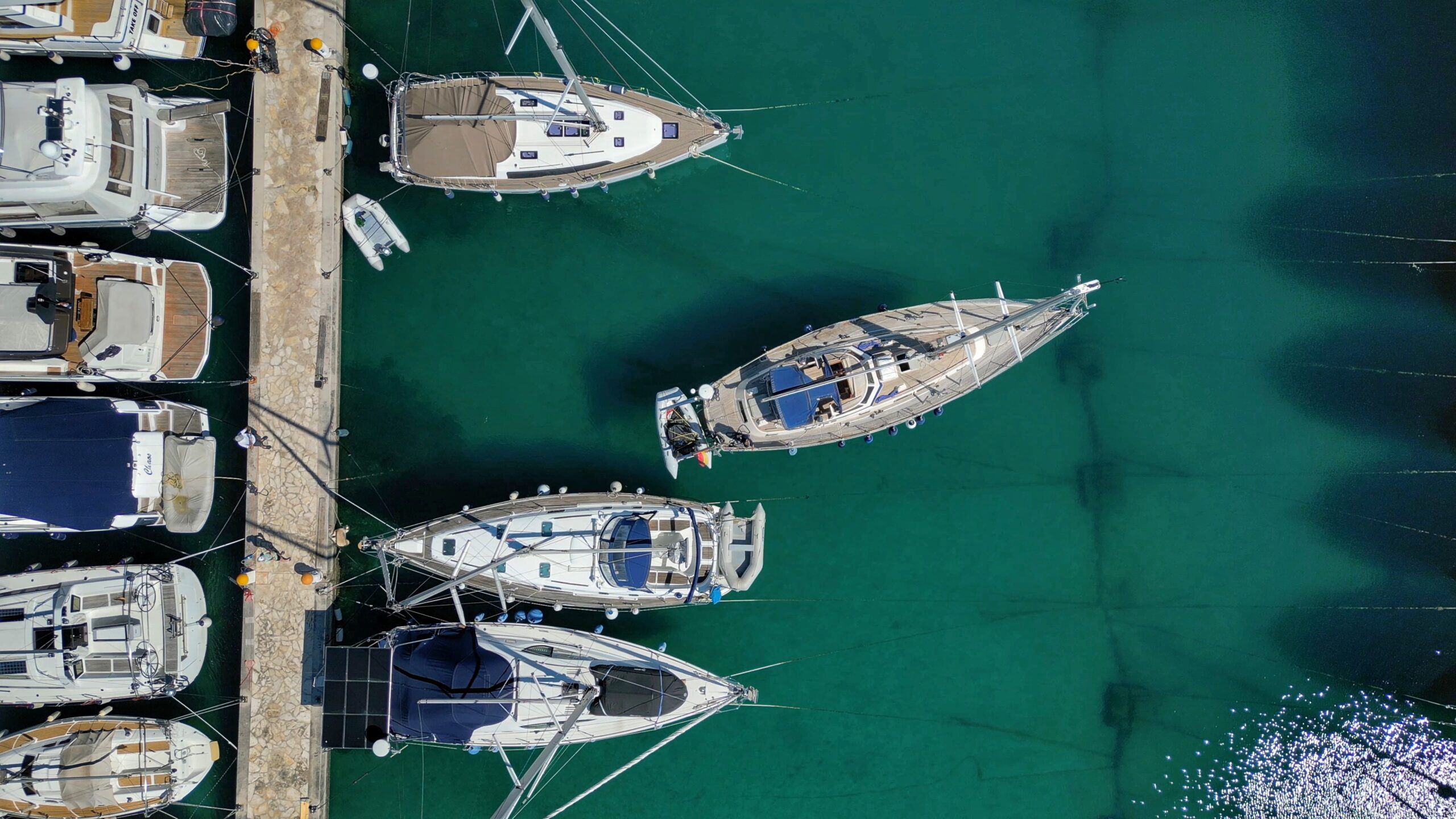 Monohull sailboat manoeuvring calmly under engine power near a pontoon, demonstrating controlled boat handling skills.