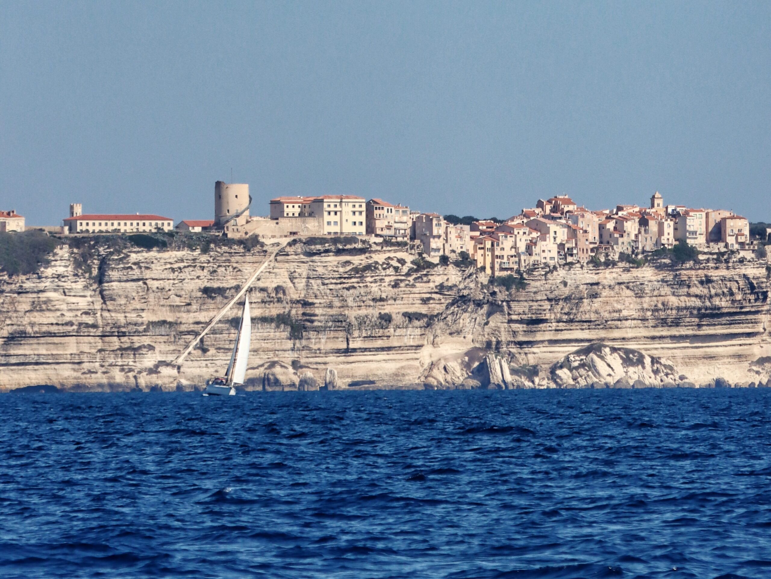 Yacht sailing past white cliffs into Bonifacio harbor Corsica Sardinia crossing