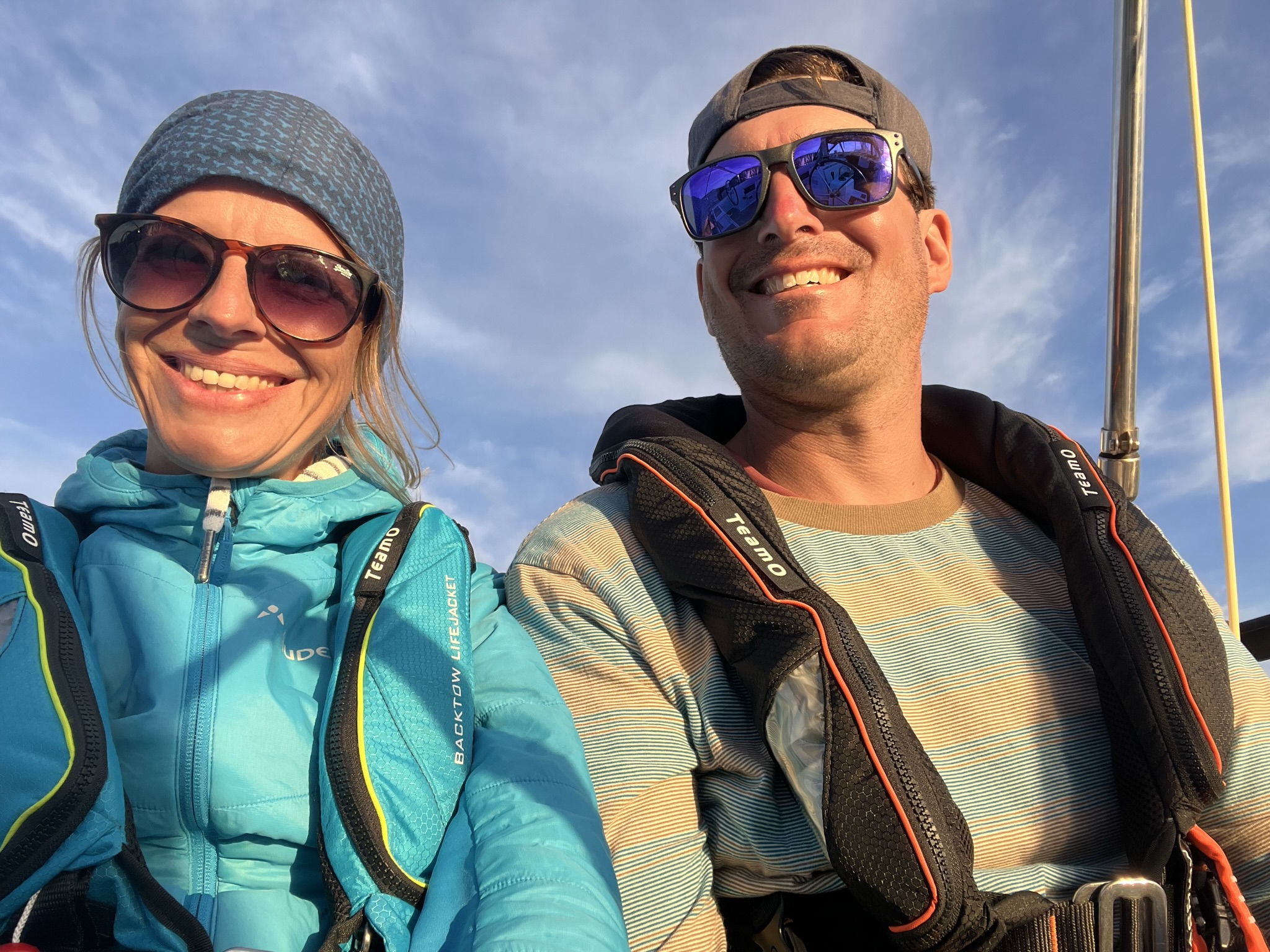 Dave and Karin wearing sailing jackets and safety lifejackets on deck.