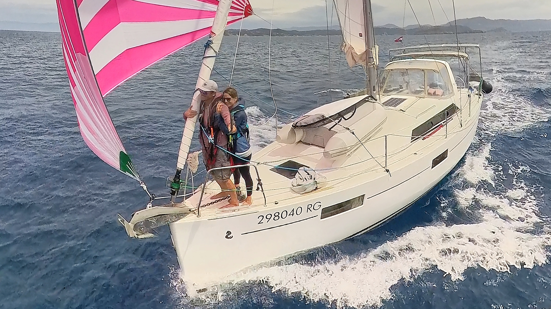 Couples sailing team flying a pink gennaker downwind on their Beneteau cruising yacht All Winds.