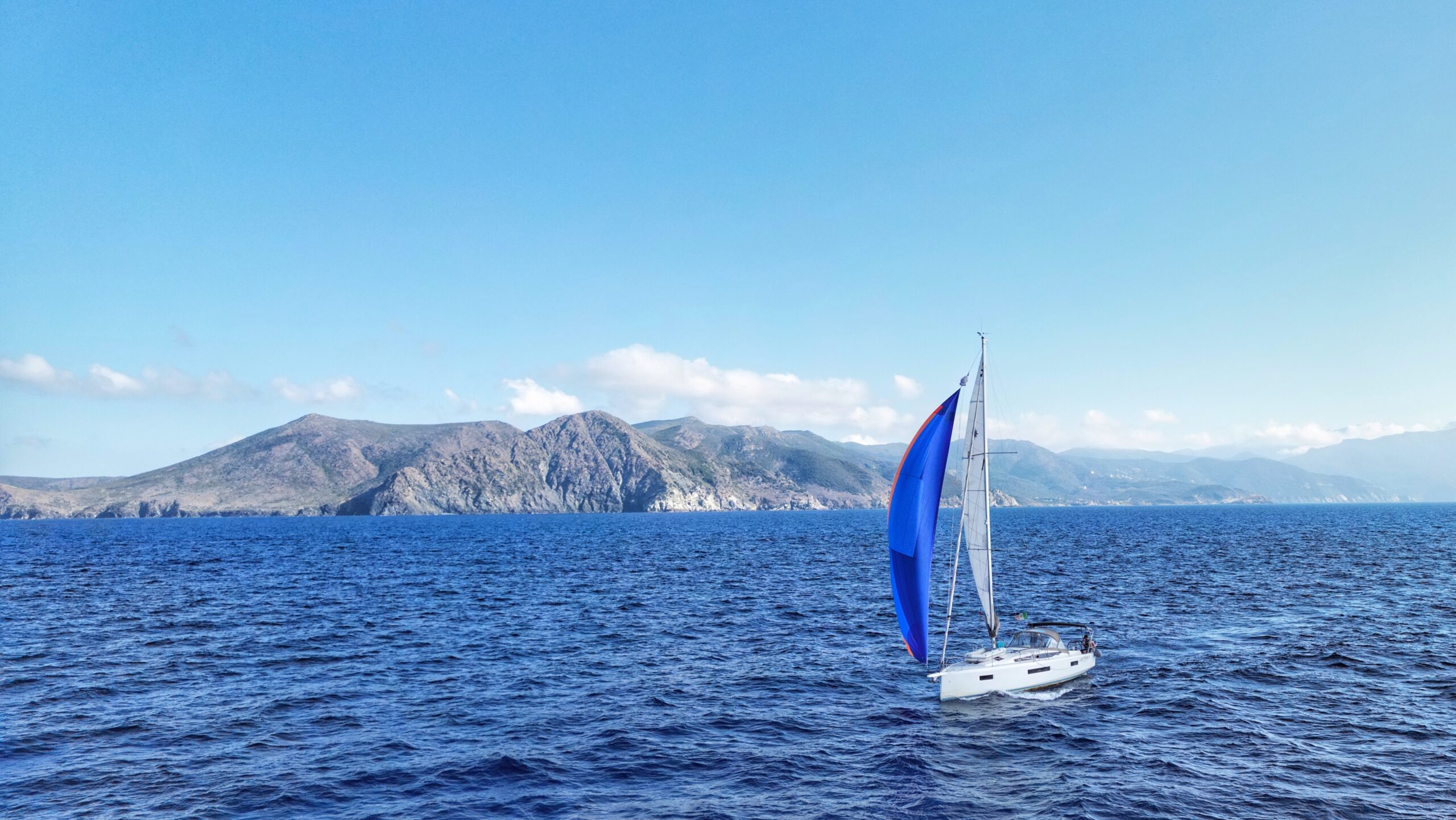 Cruising sailboat flying an asymmetric spinnaker on open coastal sea water
