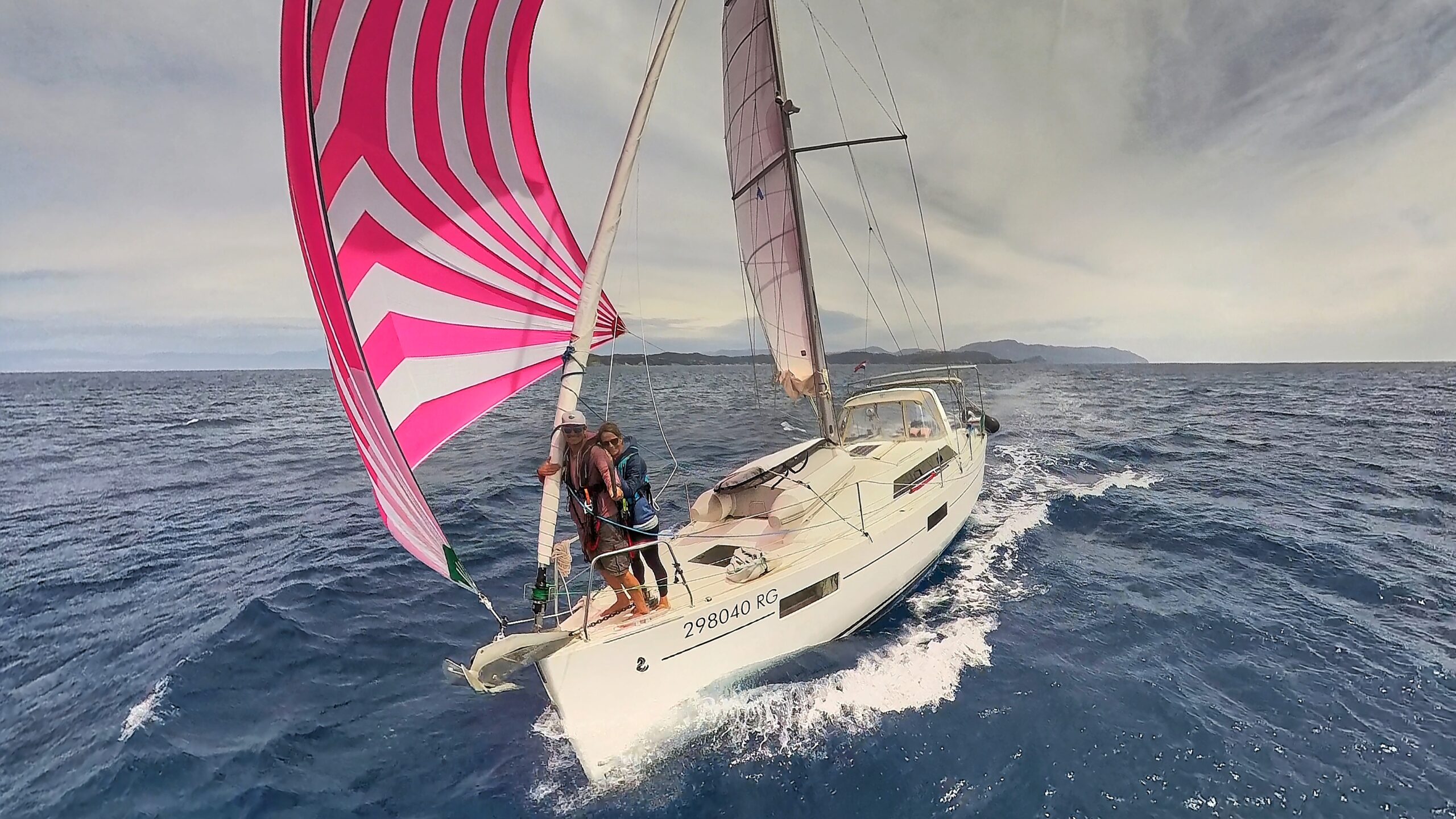 Couples sailing team flying a pink gennaker downwind on their Beneteau cruising yacht All Winds.